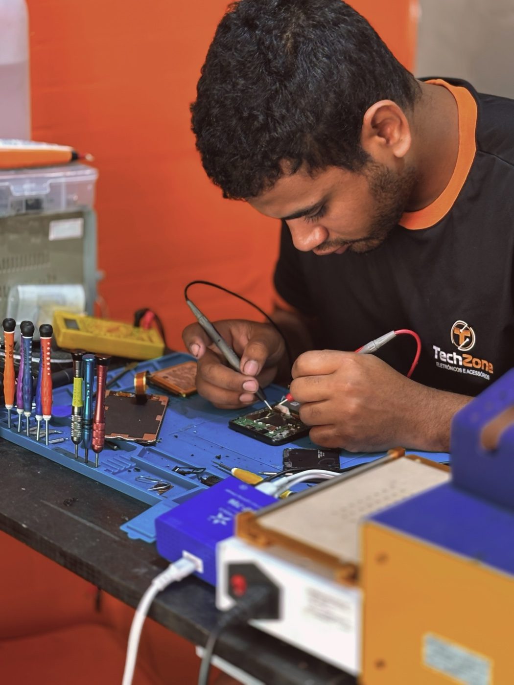 Técnico da TechZone realizando microssoldagem em placa de celular